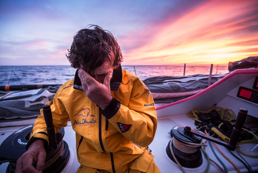 May 5, 2015. Leg 6 Newport onboard Abu Dhabi Ocean Racing. Day 16.  Roberto Bermudez 'Chuny' wipes his eyes backlit by a magnificent sunset over the Atlantic Ocean.  (Photo by Matt Knighton / Abu Dhabi Ocean Racing / Volvo Ocean Race)